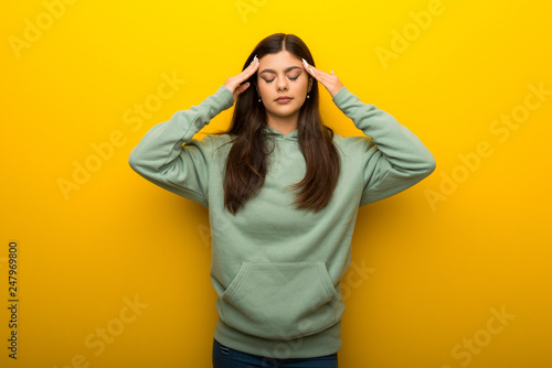 Teenager girl with green sweatshirt on yellow background unhappy and frustrated with something © luismolinero
