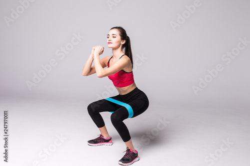 Athletic girl working with resistance band. Portrait of attractive girl with beautiful athletic body isolated on white background. Strength and motivation