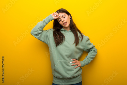Teenager girl with green sweatshirt on yellow background with tired and sick expression © luismolinero