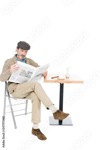 Foto senior man reading newspaper while sitting on chair with crossed legs isolated o