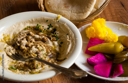 Fresh delicious hummus with broad beans dish, pita bread and colorful spicy pickles (hot chili pepper, cauliflower, cucumbers, turnip) served in the traditional restaurant in Jaffa (Israel) photo