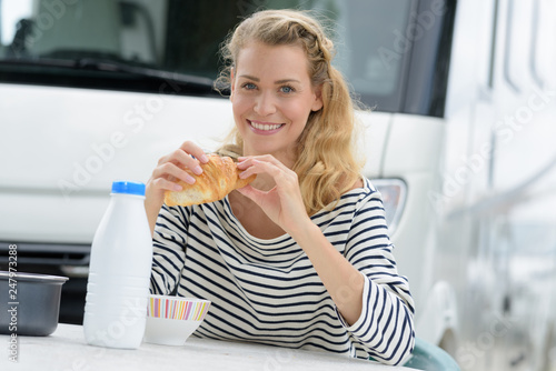 young woman having breakfast outside campervan