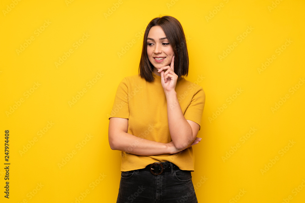 Young woman over yellow wall looking to the side Young woman over yellow wall looking to the side
