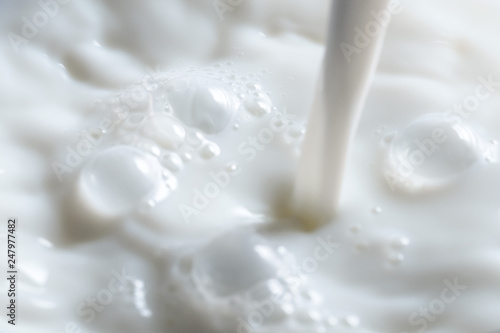 Pouring fresh milk into glass close up.