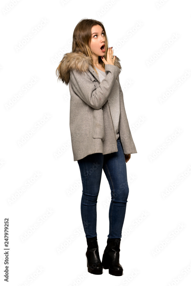 A full-length shot of a Teenager girl with coat yawning and covering wide open mouth with hand on isolated white background A full-length shot of a Teenager girl with coat yawning and covering wide open mouth with hand on isolated white background
