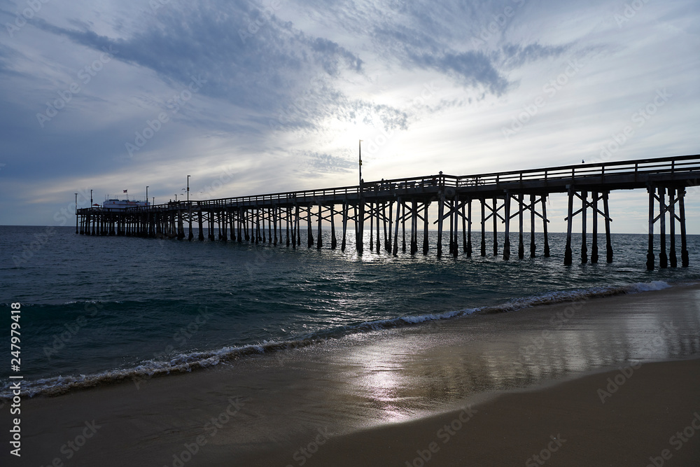 The pier at NEwport Beach in California with silhouettes of people enjoying their time at the beach