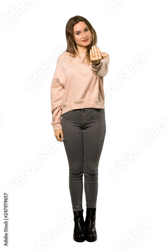 A full-length shot of a Teenager girl with pink sweater inviting to come with hand. Happy that you came over isolated white background