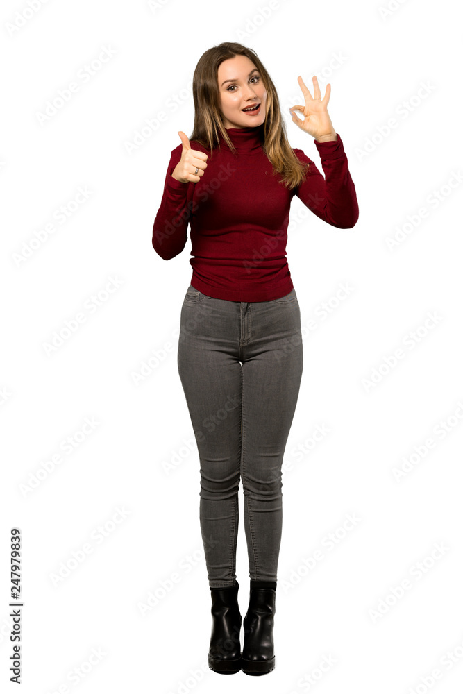 A full-length shot of a Teenager girl with turtleneck showing ok sign with and giving a thumb up gesture over isolated white background A full-length shot of a Teenager girl with turtleneck showing ok sign with and giving a thumb up gesture over isolated white background