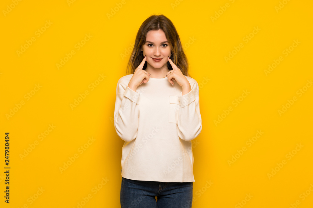 Fototapeta premium Teenager girl over yellow wall smiling with a happy and pleasant expression