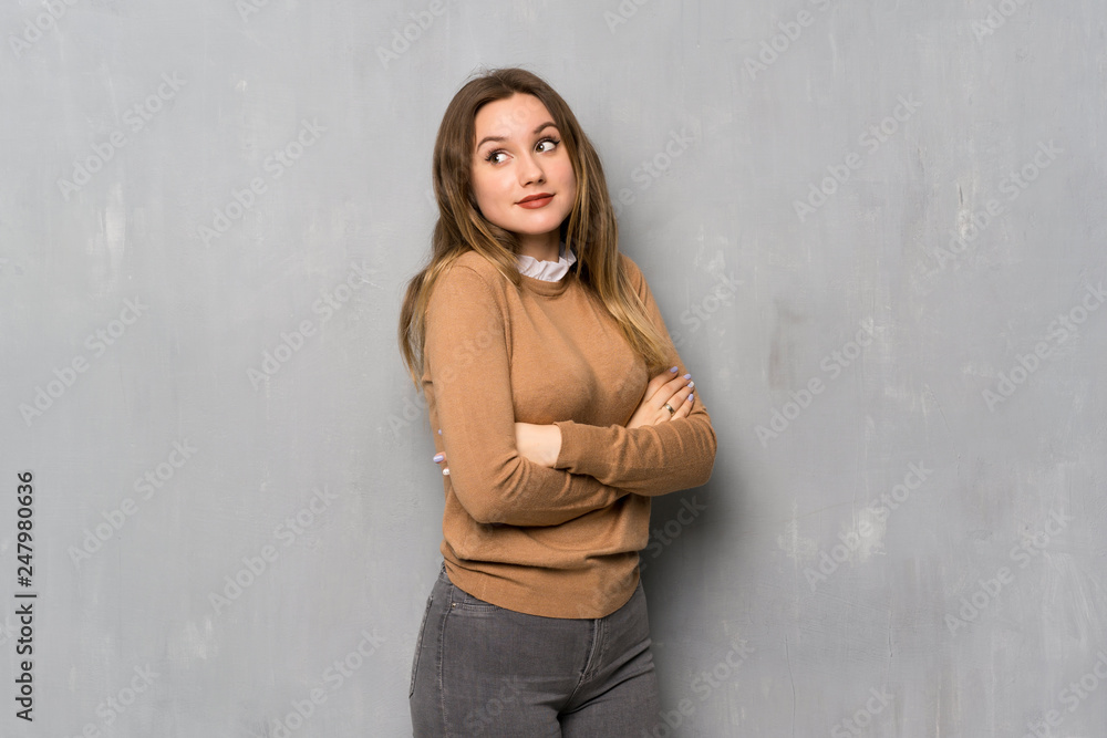 Teenager girl over textured wall making doubts gesture while lifting the shoulders Teenager girl over textured wall making doubts gesture while lifting the shoulders