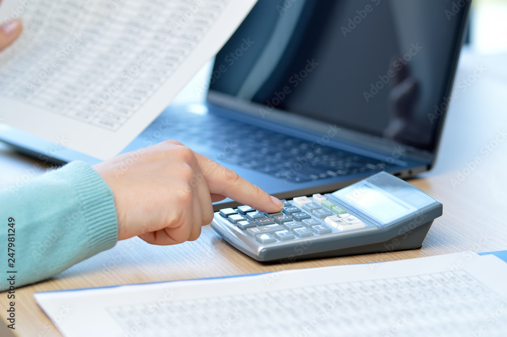 Accountant calculating with a calculator on a desk at office Accountant calculating with a calculator on a desk at office