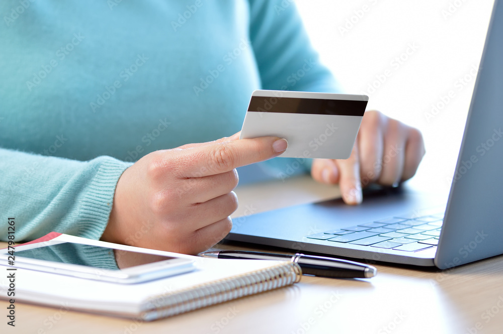Woman hand paying on line with credit card at home