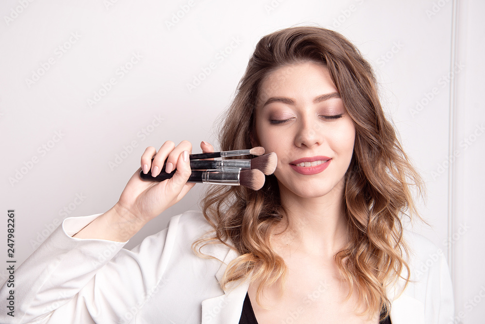 Cute brunette make-up artist using makeup brush Cute brunette make-up artist using makeup brush