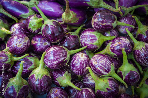 Close up on small round purple eggplants for sale at a farmers market