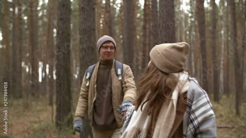 Wallpaper Mural Young woman smiling and holding hands with her boyfriend while walking together through pine forest on autumn day Torontodigital.ca