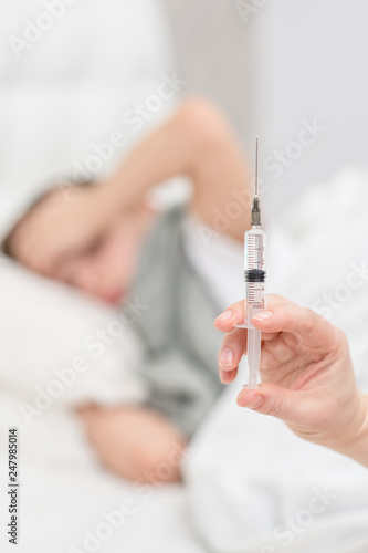 Close up view of a syringe with a child at the background
