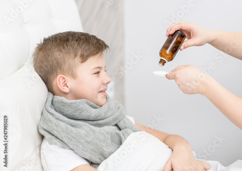 Sick little boy awaits her medication pouring in a spoon photo