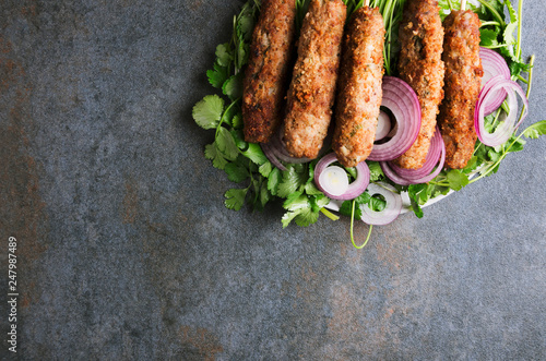 Top view of type of kebab-lule kebab with herbs and sliced onion on dark table.Copy space for text photo