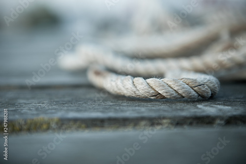 Close up of a sailing rope on a wooden pier with depth of fields 