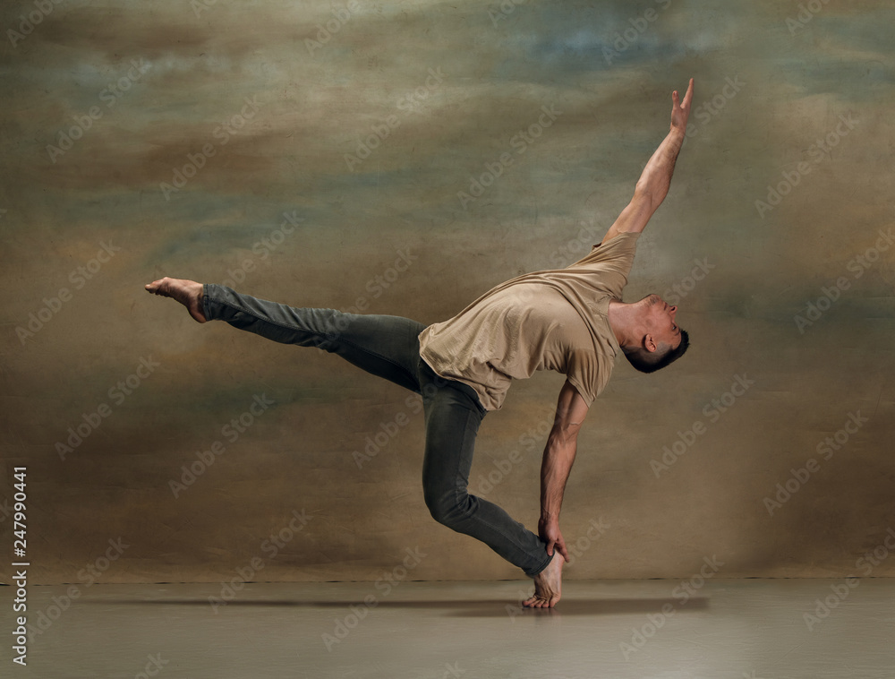 Fototapeta premium The young man dancing in contemporary stile of ballet at studio on gray background