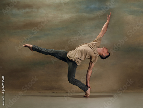 The young man dancing in contemporary stile of ballet at studio on gray background