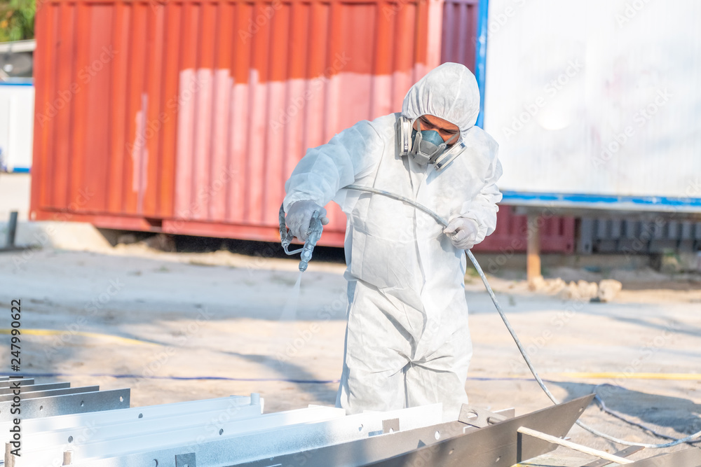 worker painting a mechanical part with airless spray