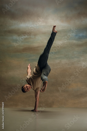 Fototapeta Naklejka Na Ścianę i Meble -  The young man dancing in contemporary stile of ballet at studio on gray background