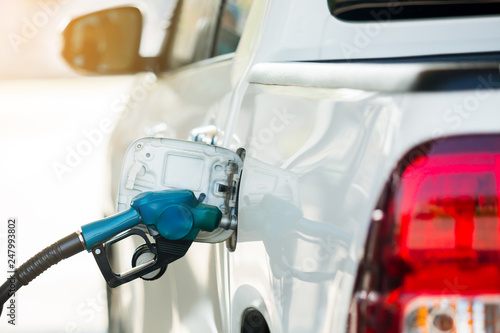 Hand refilling the white pickup truck with fuel at the gas station