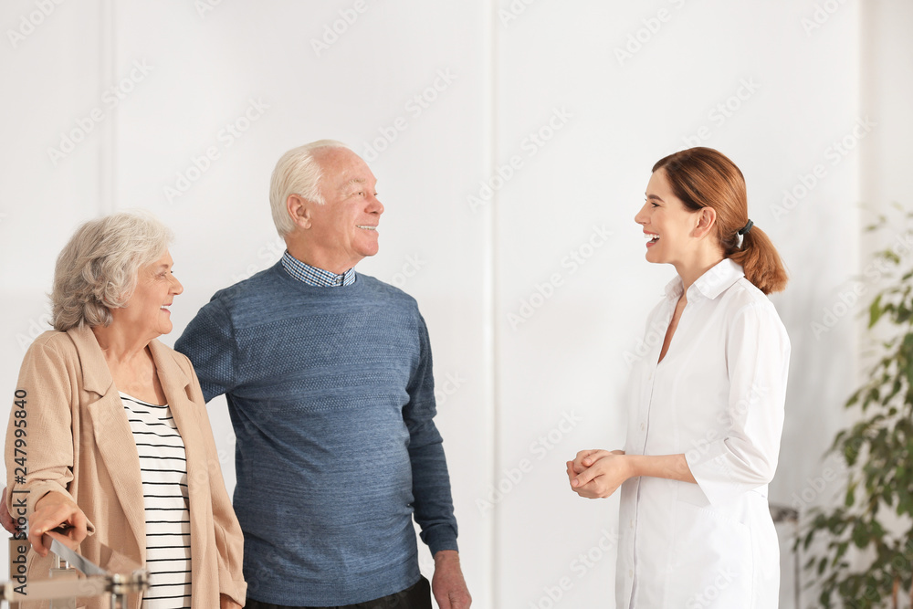 Elderly spouses with female caregiver in room Elderly spouses with female caregiver in room