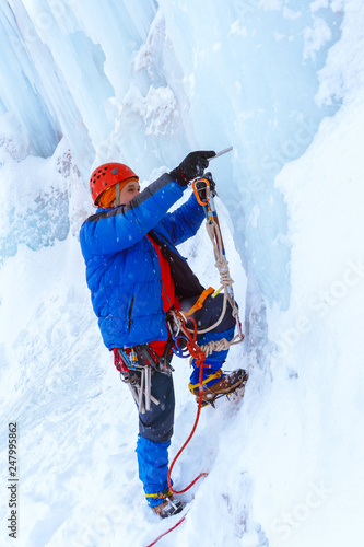 rock climber screwing ice screw into glacier surface