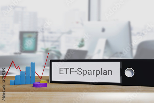 Investment in Aktienfonds. Akten-Ordner beschriftet mit dem Begriff ETF-Sparplan liegt neben Diagrammen auf einem Schreibtisch. Büro im Hintergrund. photo