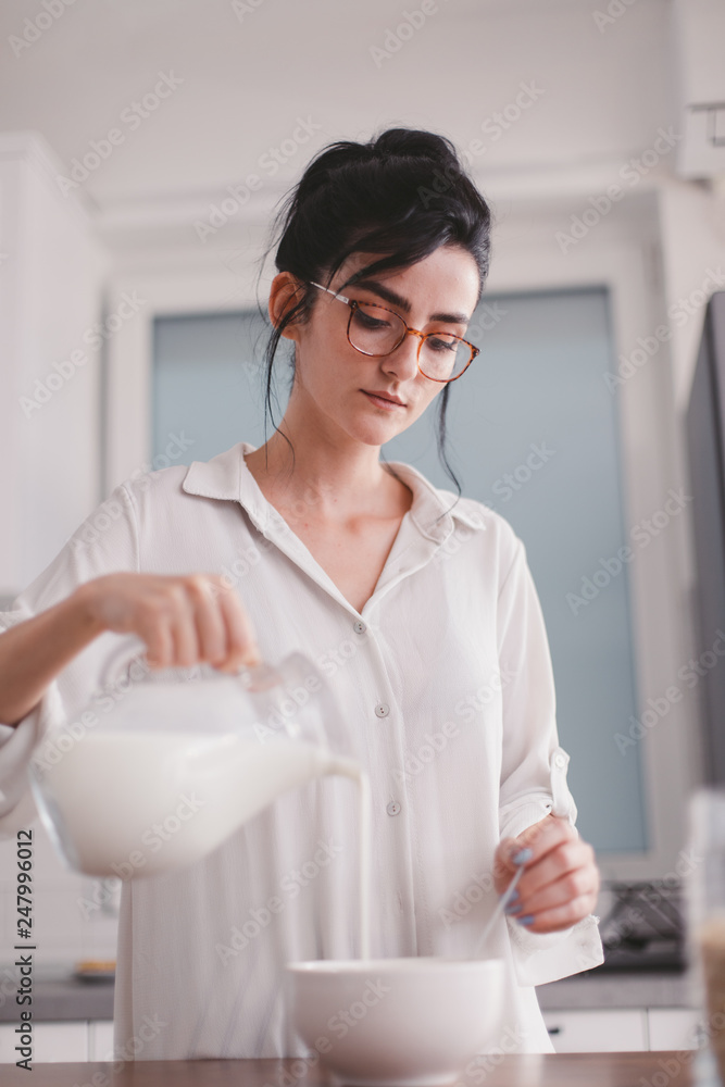 Beautiful young woman pouring milk in a bowl Beautiful young woman pouring milk in a bowl