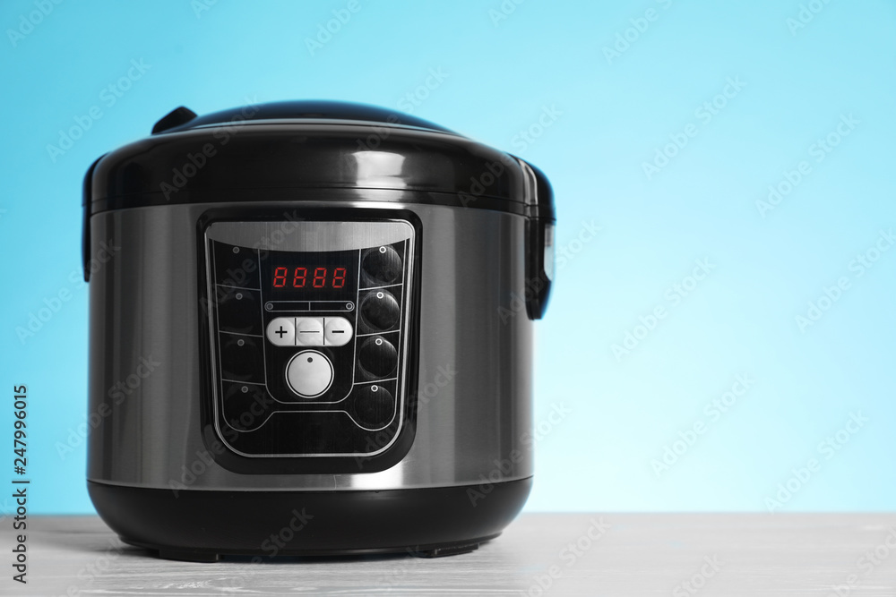 Fototapeta premium Modern electric multi cooker on table against color background. Space for text
