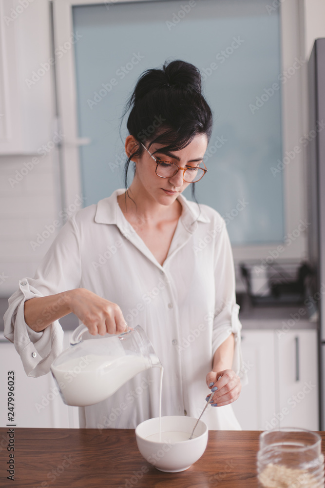 Beautiful young woman pouring milk in a bowl Beautiful young woman pouring milk in a bowl