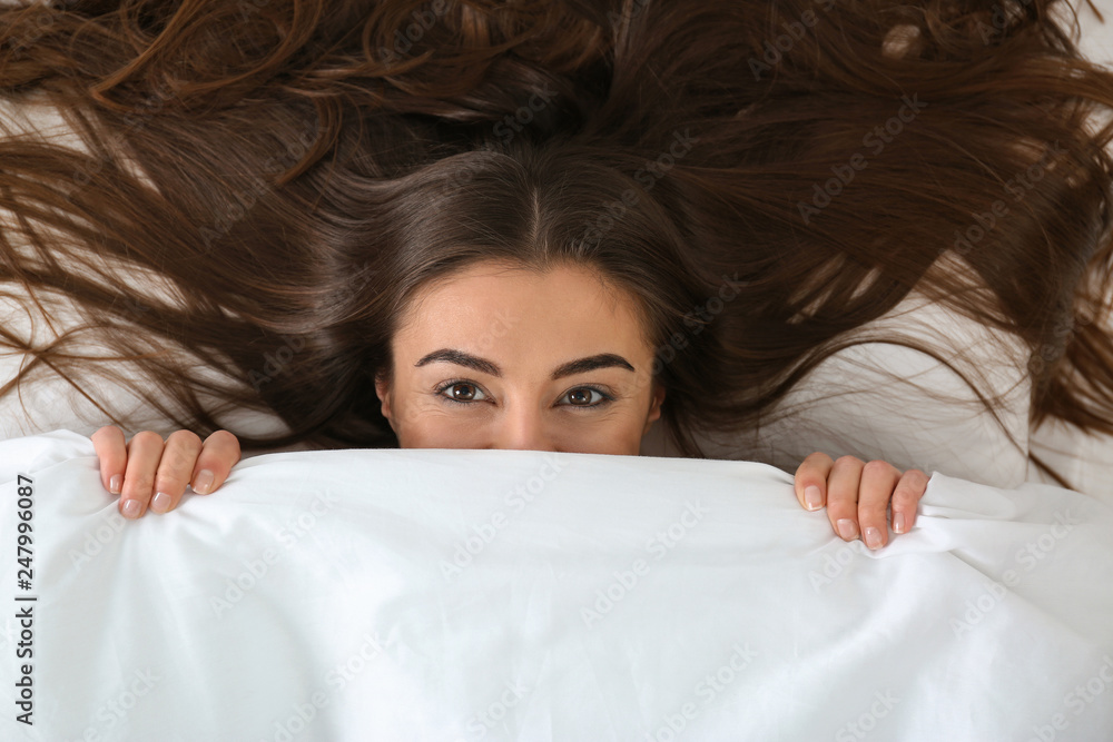Young woman lying under blanket, top view. Bedtime Young woman lying under blanket, top view. Bedtime