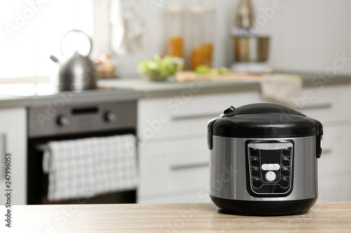 Modern electric multi cooker on table in kitchen. Space for text