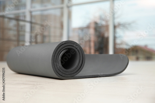 Rolled grey yoga mat on floor indoors