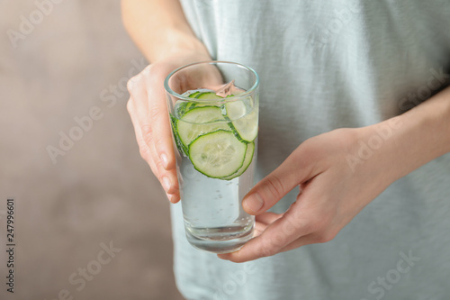 Young woman holding glass with fresh cucumber water, closeup. Space for text