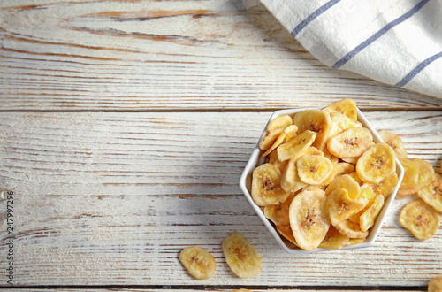 Bowl with sweet banana slices on wooden table, top view with space for text. Dried fruit as healthy snack