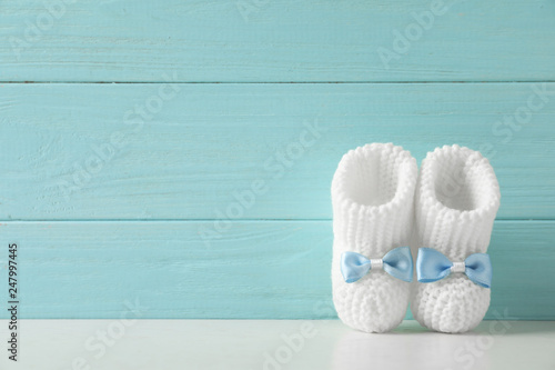 Handmade baby booties on table against wooden background. Space for text