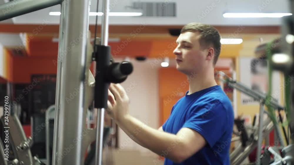 Medium shot male adjusting smith machine in the gym before workout. Shallow depth of field Medium shot male adjusting smith machine in the gym before workout. Shallow depth of field