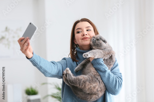 Young woman taking selfie with her cute cat at home