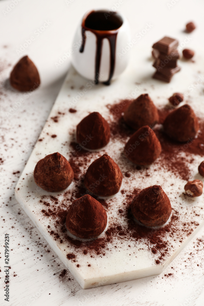 Board with tasty sweet truffles on white table Board with tasty sweet truffles on white table