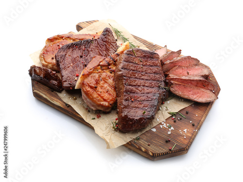 Wooden board with different tasty cooked meat on white background