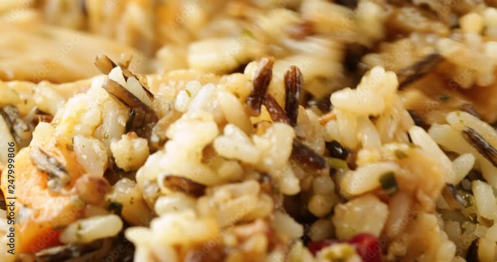 Very close video of stirring a chicken with pecans and wild rice TV dinner in a plastic tray with a fork then taking a bite at the end illuminated with natural lighting. Very close video of stirring a chicken with pecans and wild rice TV dinner in a plastic tray with a fork then taking a bite at the end illuminated with natural lighting.