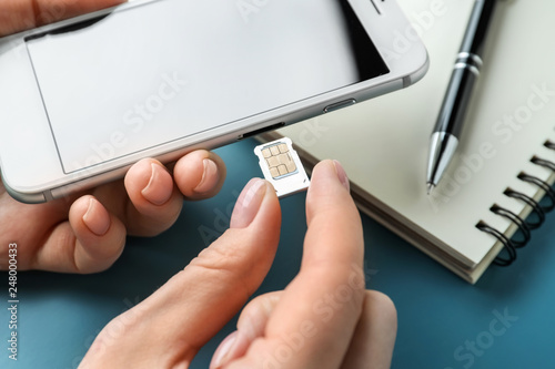 Woman inserting sim card into mobile phone, closeup