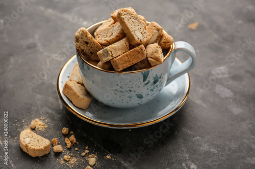 Cup with tasty Italian biscotti on grey table photo