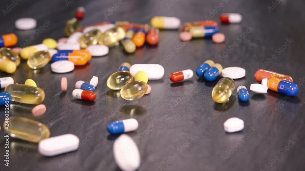 Mixed colorful medicals falling on black surface - slow motion close up Mixed colorful medicals falling on black surface - slow motion close up