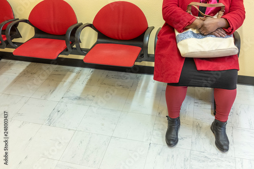 Health care: view of feets of a woman in red in doctor's waiting room