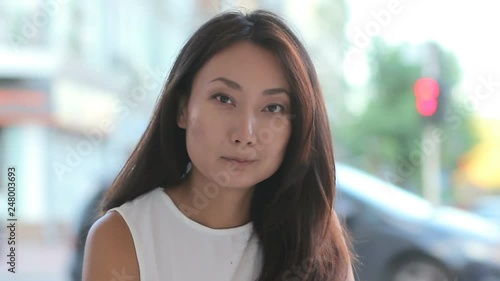 Young asian business woman portrait serious and confident looking at camera sitting outdoor on urban background